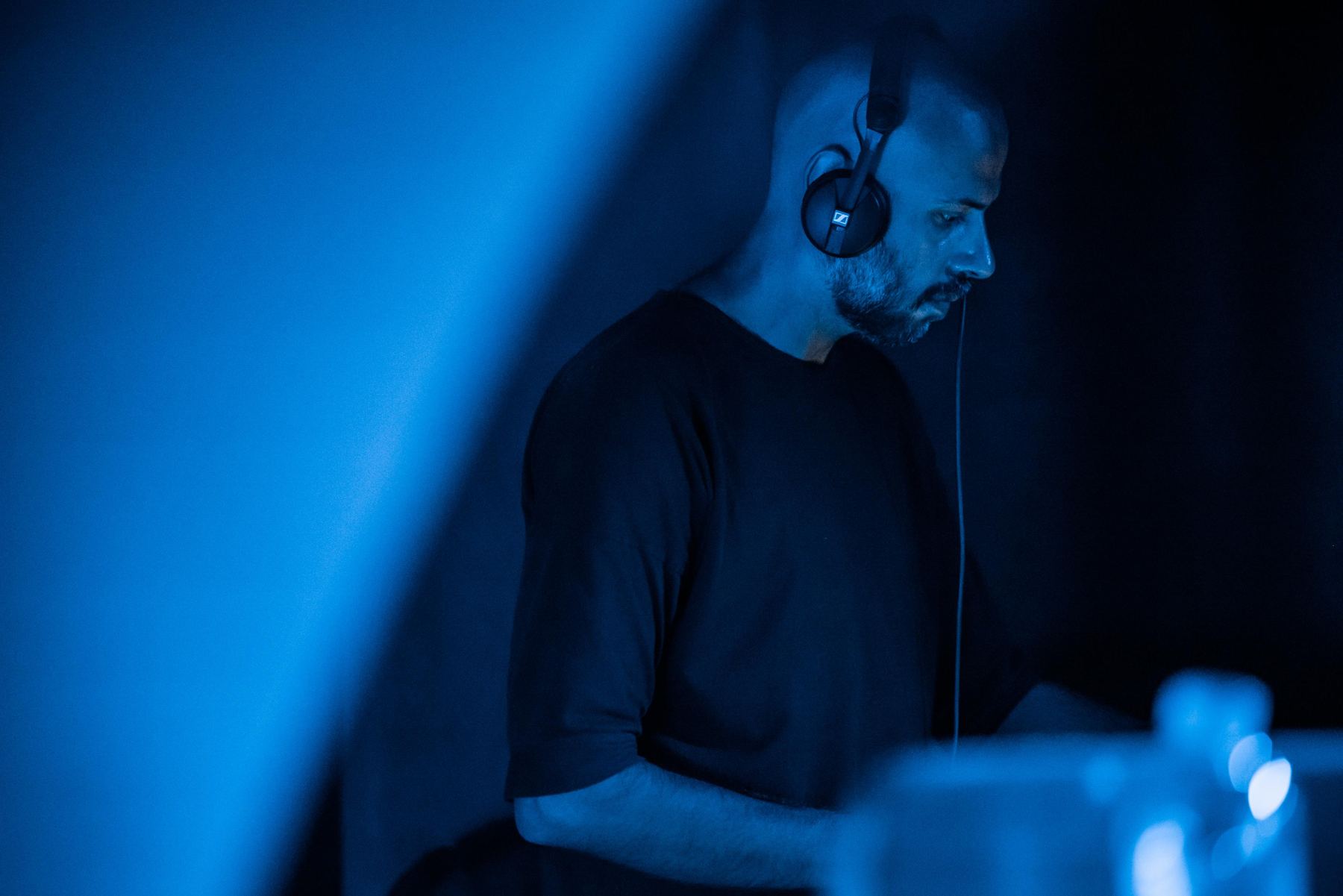 Talos at the decks in blue light, wearing headphones
